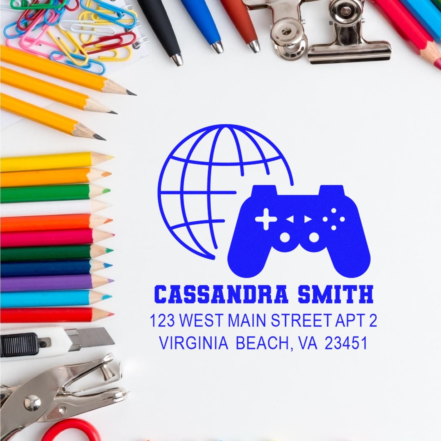 Personalized rubber address stamp with gamer globe logo and name, surrounded by stationery on a white background.