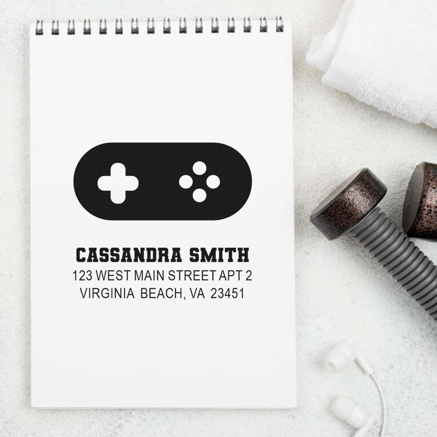 Custom rubber return address stamp with name and Virginia Beach address, shown on a notepad beside stamp parts.