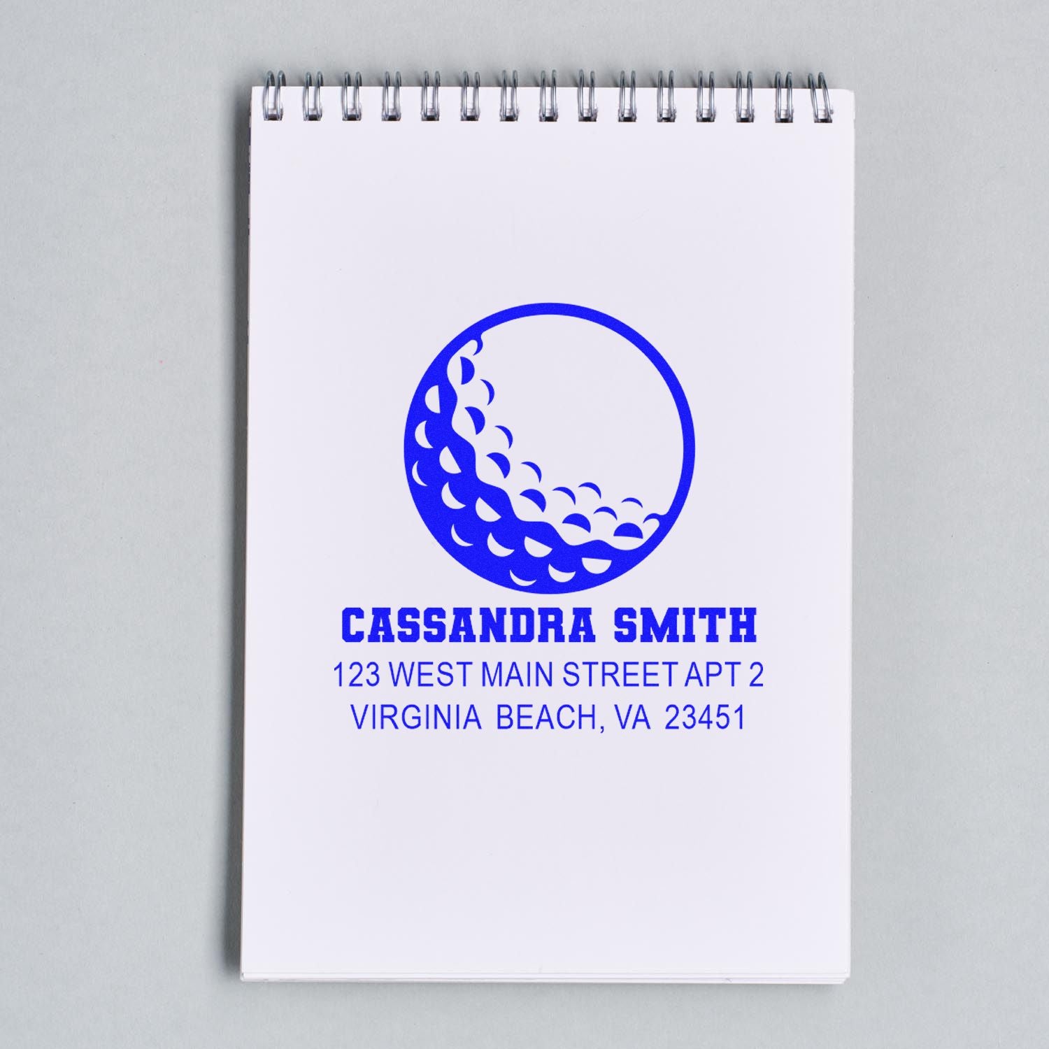 Custom blue return address rubber stamp with logo, name, and Virginia Beach address on a notepad