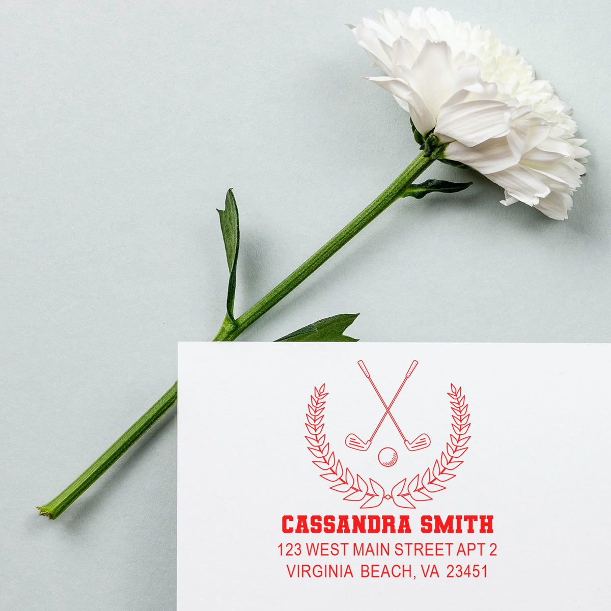 Custom golf return address rubber stamp with crossed clubs, laurel wreath, and address imprint on a white card.
