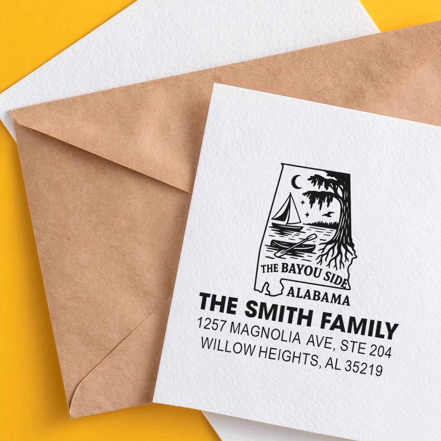 Custom return address rubber stamp on white envelope with family name, address, and Bayou Side Alabama design.