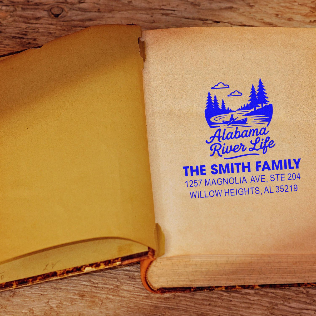 Custom rubber address stamp on book page with Alabama River Life logo, family name, and mailing address.