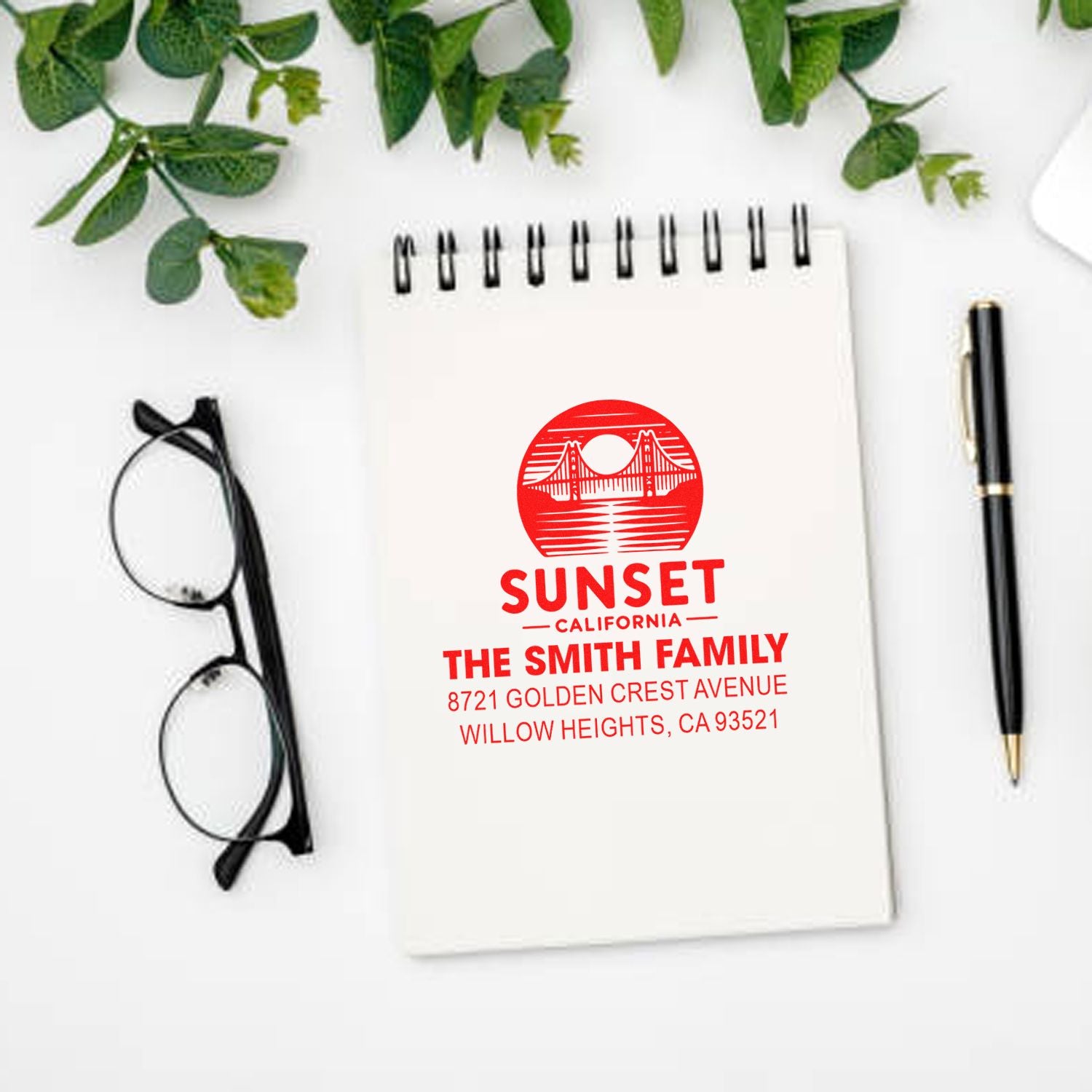 Custom personalized rubber return address stamp with bridge design for The Smith Family, Sunset California on a notebook