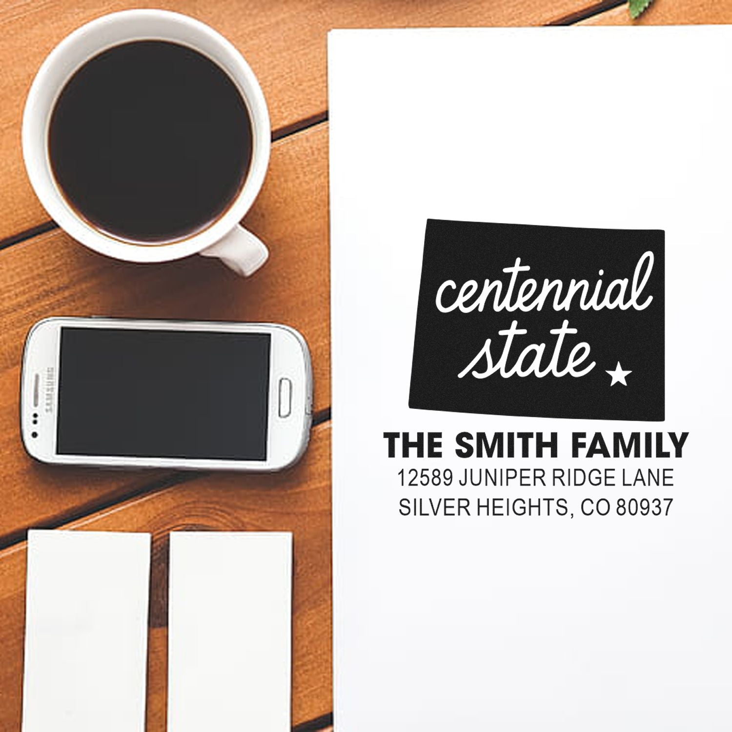 Custom return address rubber stamp with Centennial State script, family name, and Colorado mailing details.