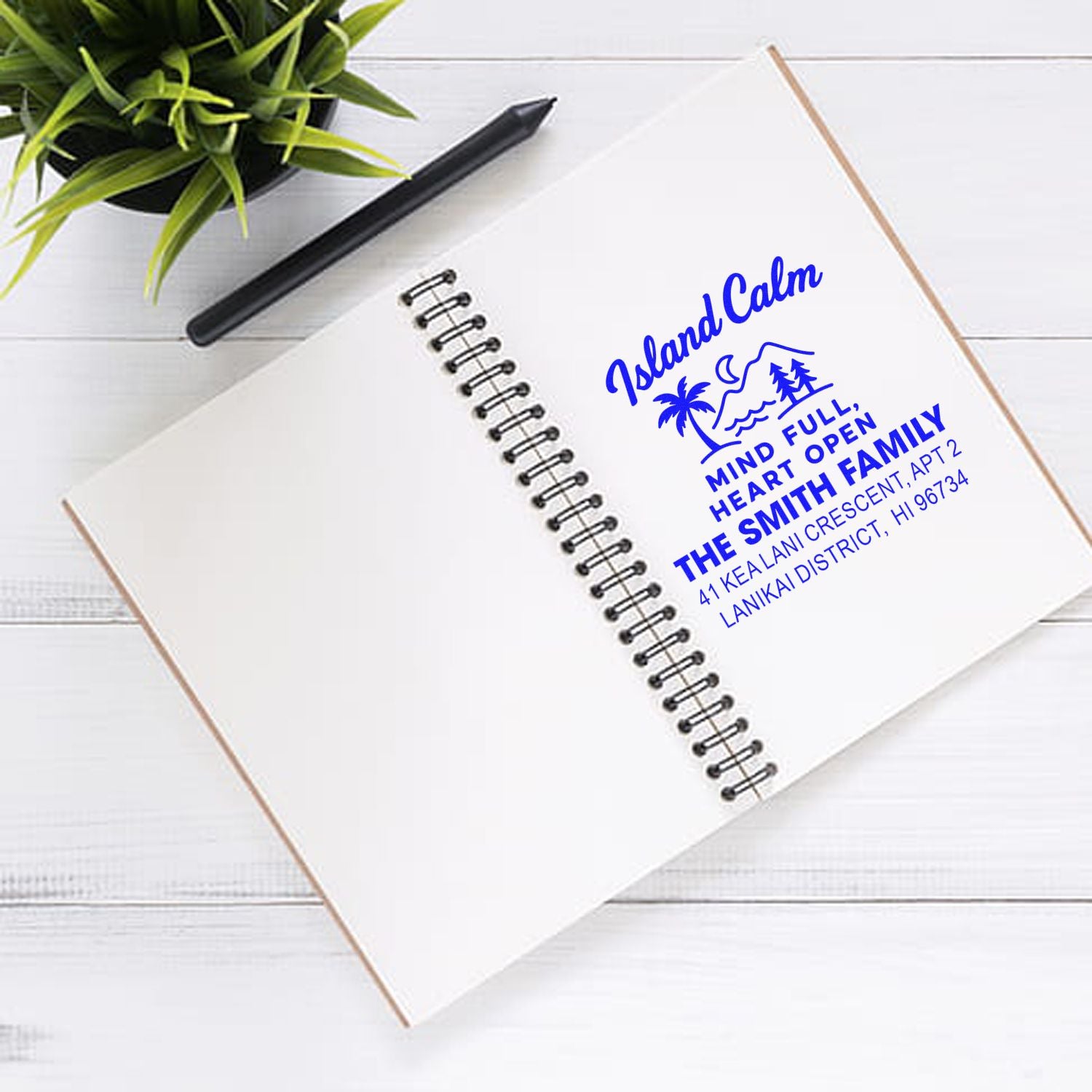 Custom rubber address stamp impression on notebook with island-themed family return address design.