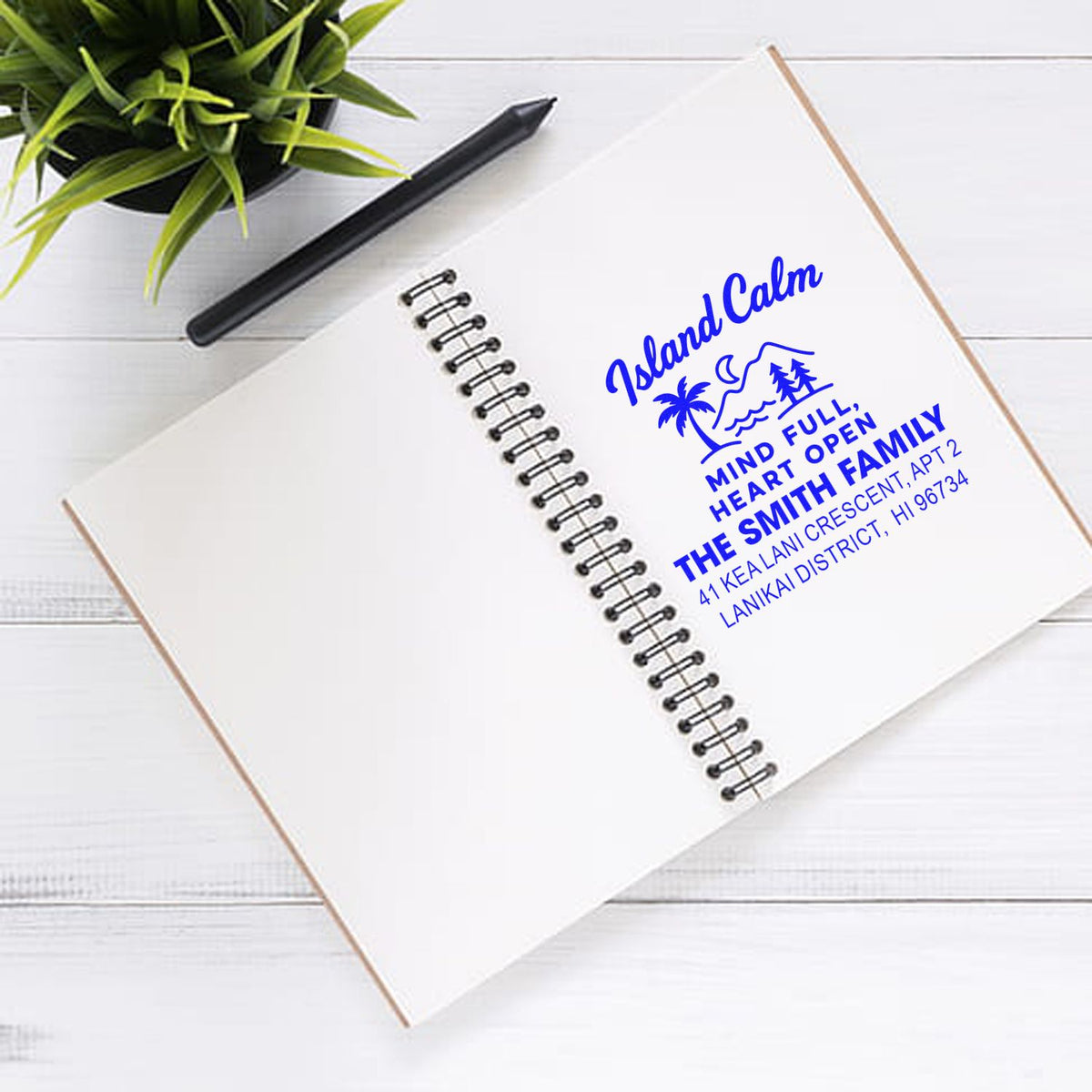 Personalized rubber return address stamp with Island Calm design, stamped in blue on a notebook page.