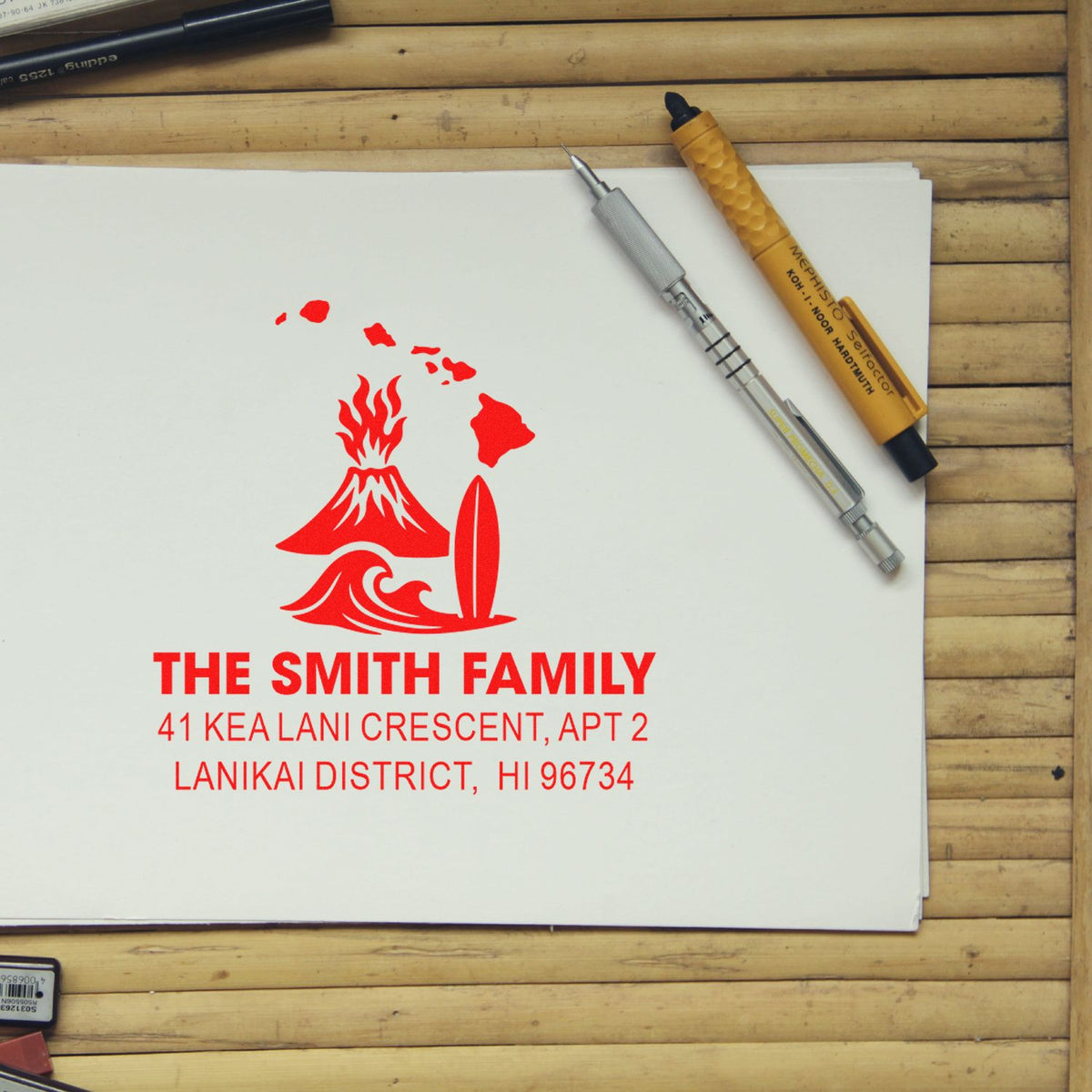Custom return address rubber stamp with Hawaii surf design, shown on paper with stamp tools on a wood desk.