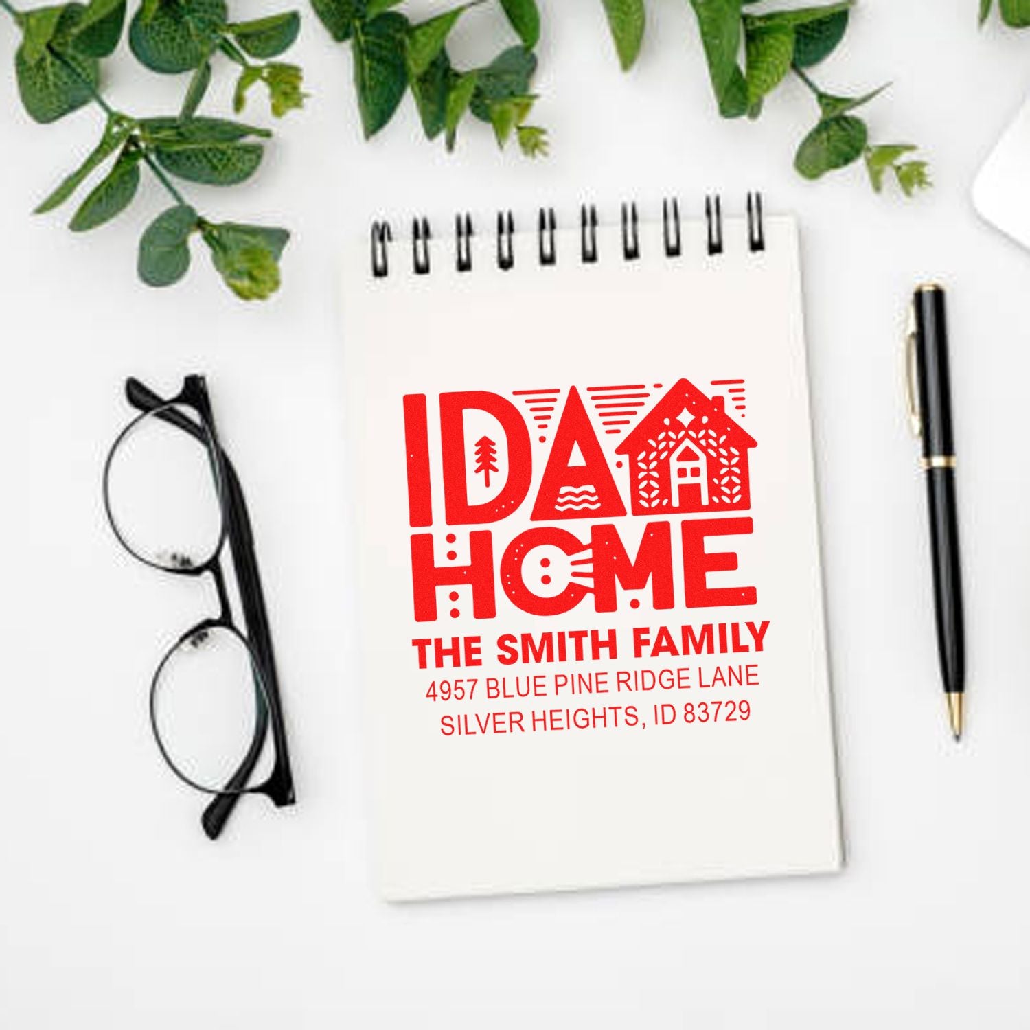 Custom return address rubber stamp mockup with IDA HOME and Smith family address on a notebook.