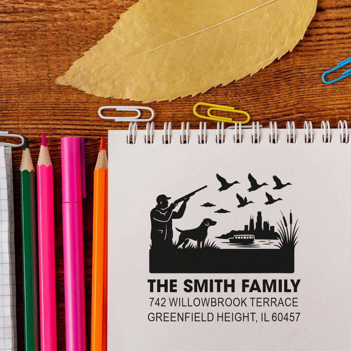 Custom family address rubber stamp with hunting scene design on notebook, featuring The Smith Family and a Greenfield Heights address.