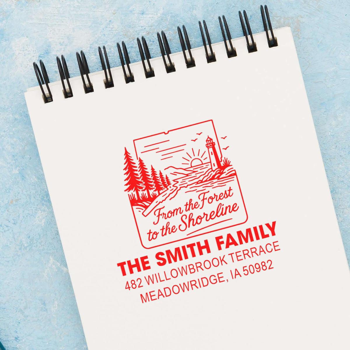 Custom lighthouse family address rubber stamp on spiral notebook, ideal for personalized stationery.