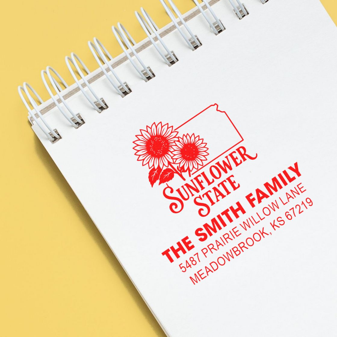 Custom sunflower family return address rubber stamp for The Smith Family, Meadowbrook, KS, shown on a notebook page.