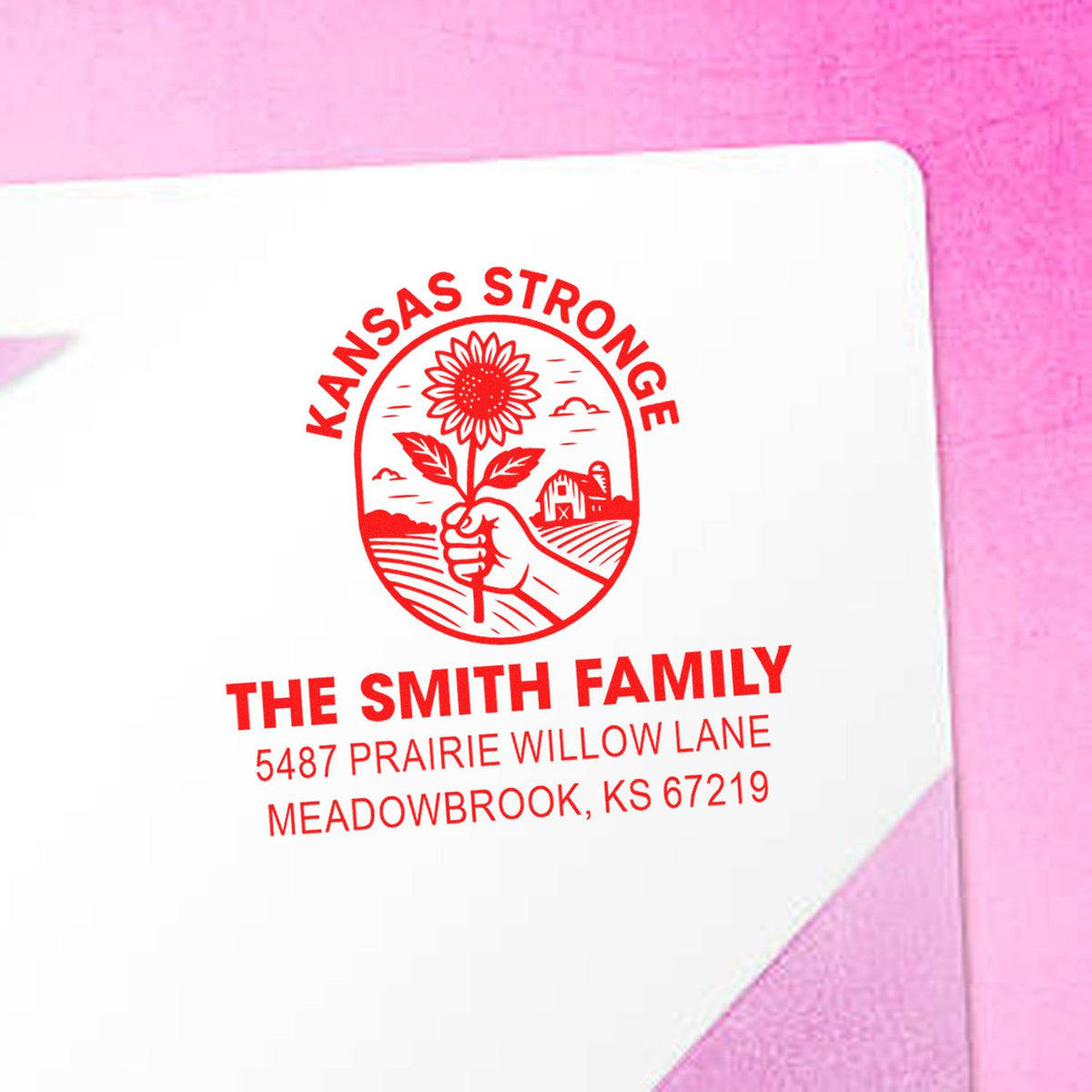 Custom return address rubber stamp with sunflower design for The Smith Family, Meadowbrook, KS, on a pink envelope.