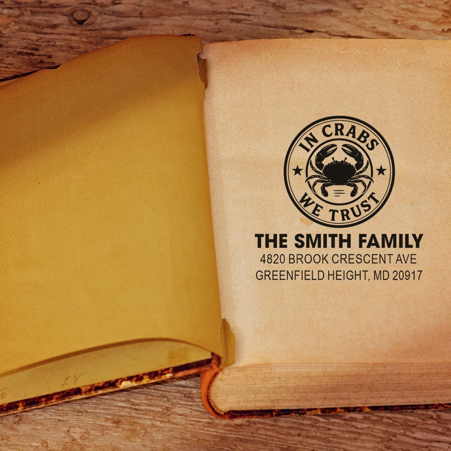 Personalized crab rubber address stamp on an open book, with family name and address for custom bookplates or mailings.