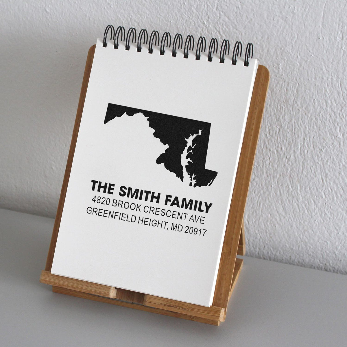 Custom Maryland family return address rubber stamp sample with state silhouette and personalized address on notebook