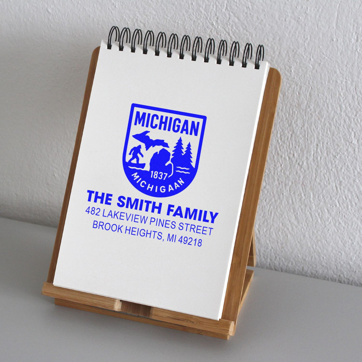Custom Michigan address rubber stamp for The Smith Family, shown on a notepad stand for personalized stationery.