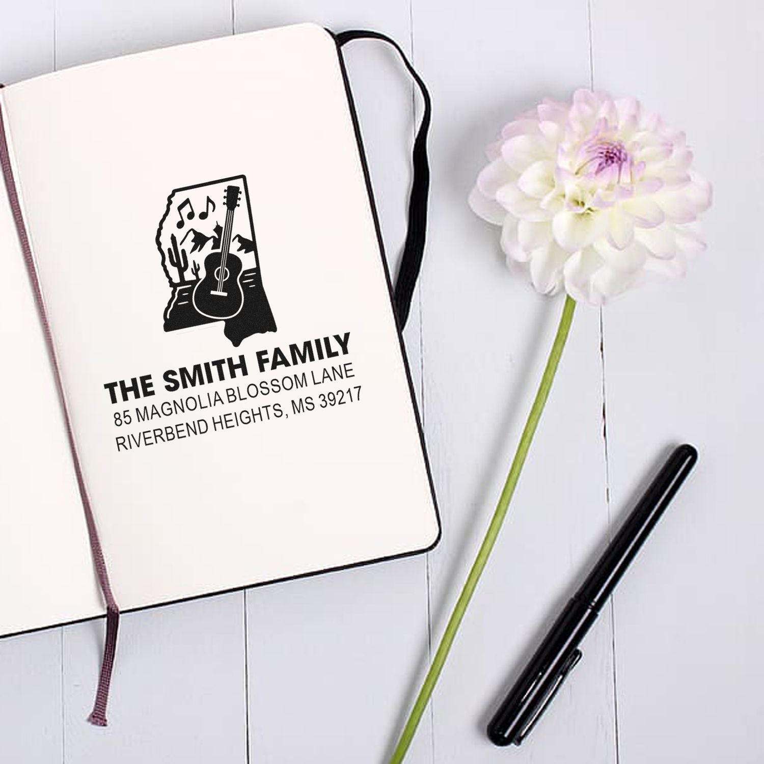 Custom family address rubber stamp design with guitar and music notes for The Smith Family on a notebook.