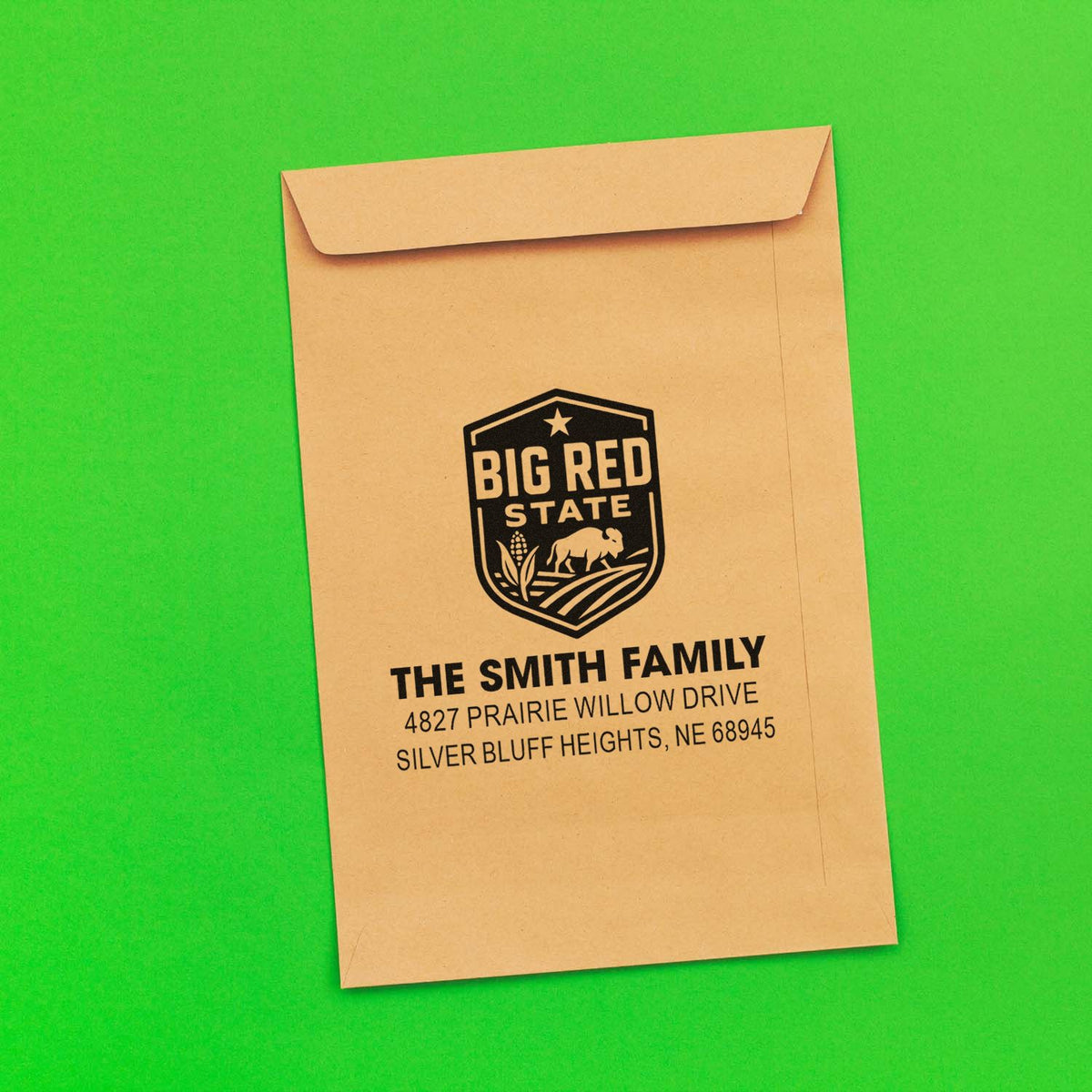 Custom family return address rubber stamp on kraft envelope with Big Red State logo for personalized mailings.