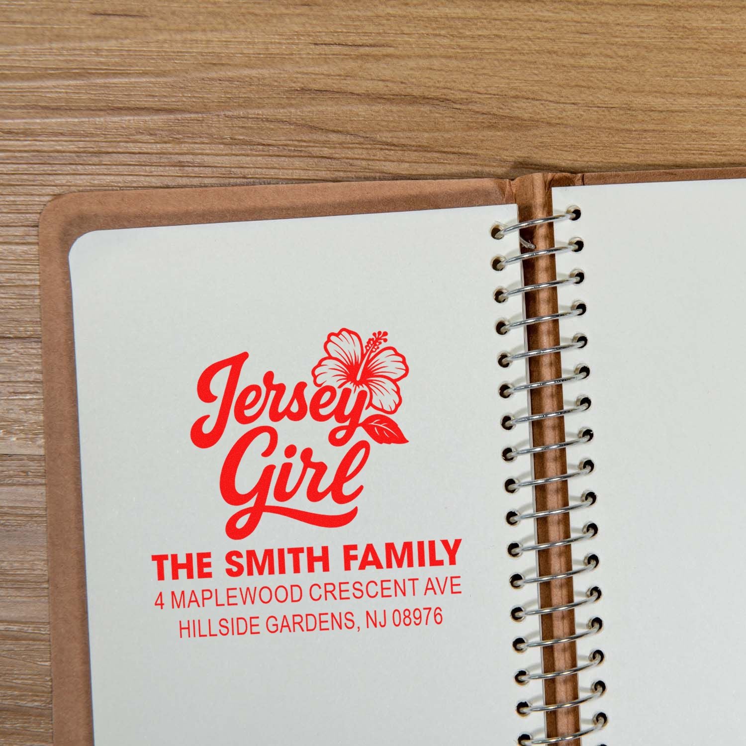 Personalized Jersey Girl return address stamp with floral design for The Smith Family, printed in red on notebook page.