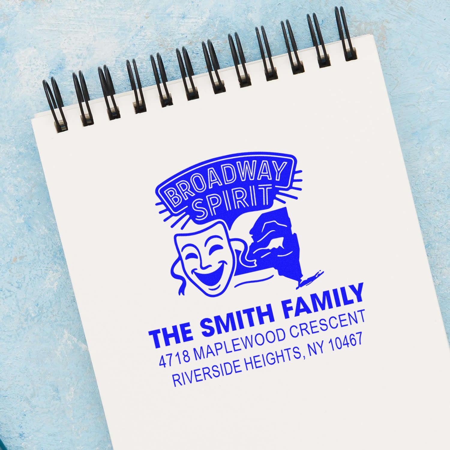 Custom rubber stamp imprint with Broadway Spirit logo and The Smith Family address on a spiral notebook