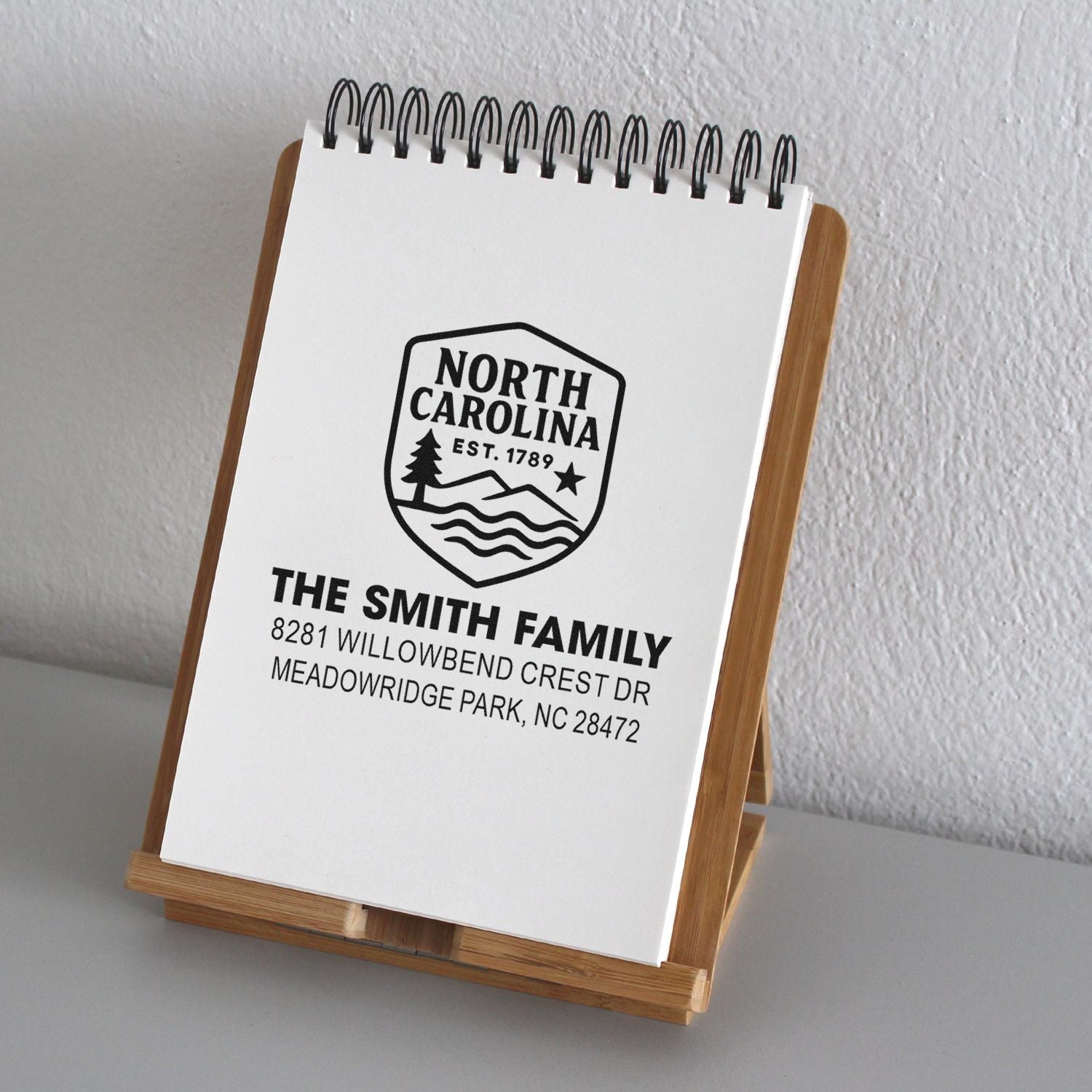 Personalized North Carolina address rubber stamp with family name and home address on notepad display.