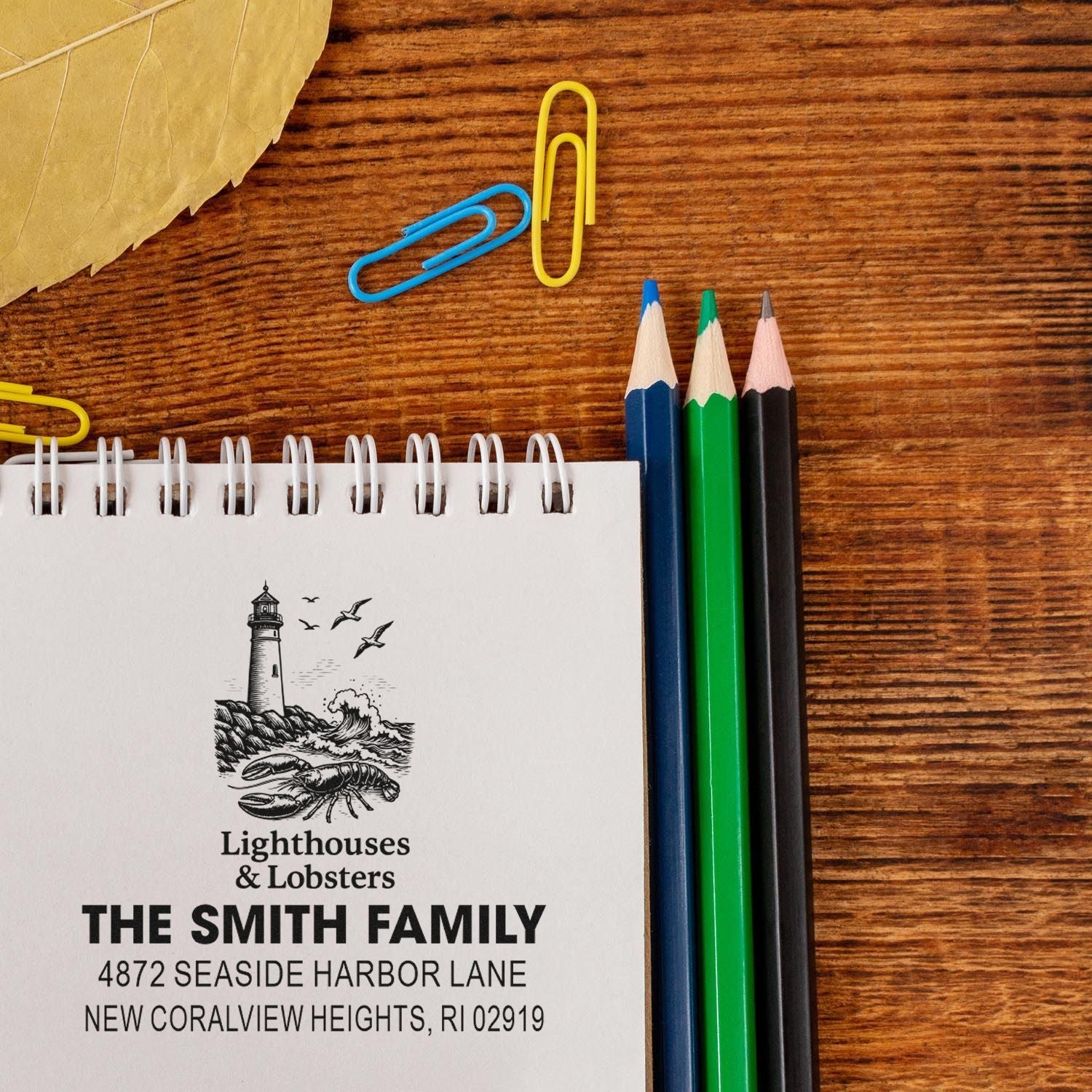 Personalized return address rubber stamp with lighthouse and lobster design for The Smith Family on a notebook.