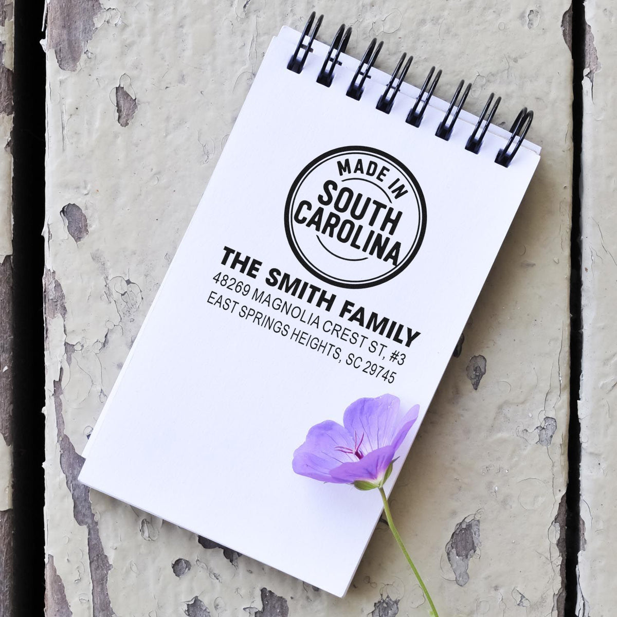 Custom address rubber stamp on spiral notebook with Made in South Carolina design and purple flower accent.