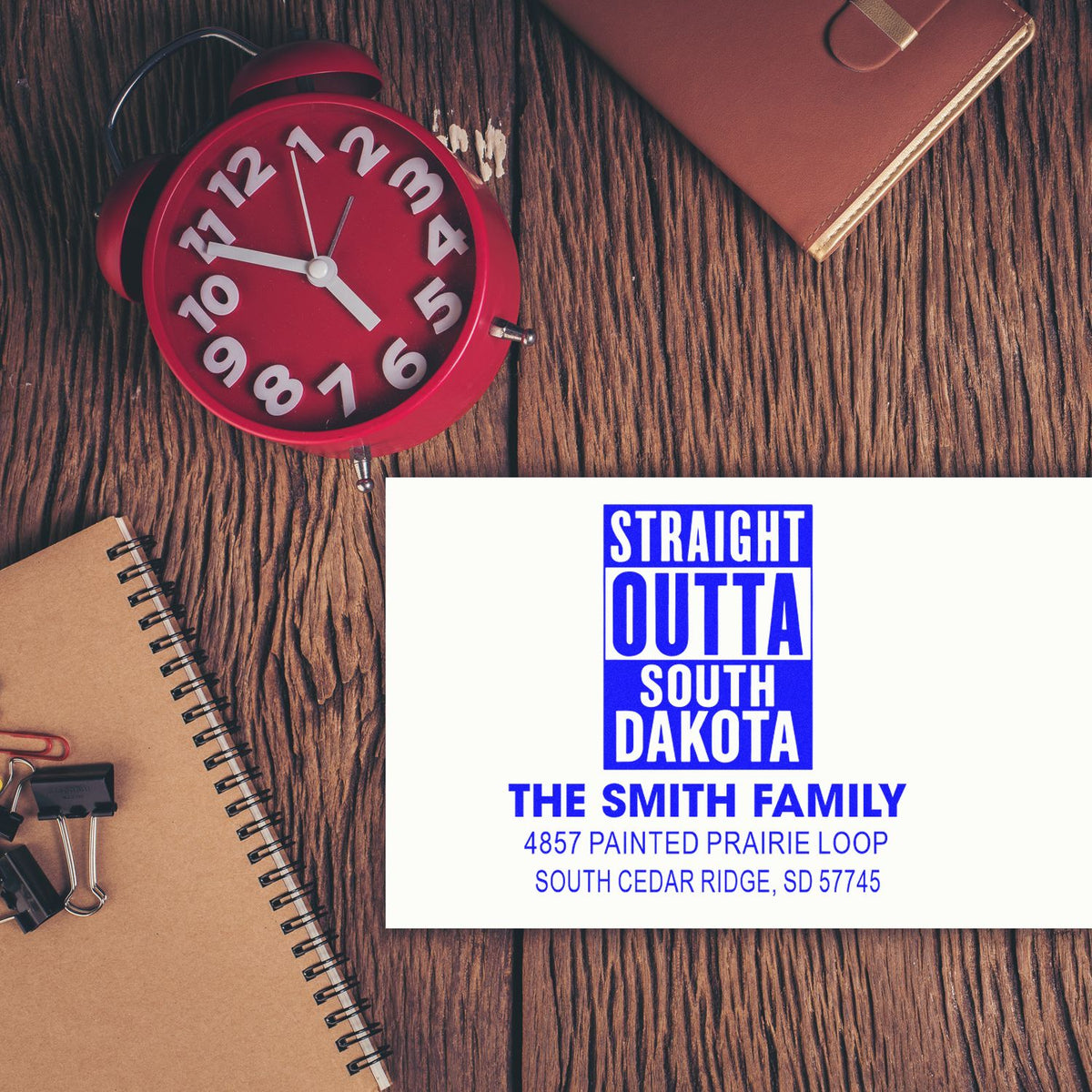 Personalized rubber stamp mockup for family mailing, featuring South Dakota address and custom name on a desk flat lay.