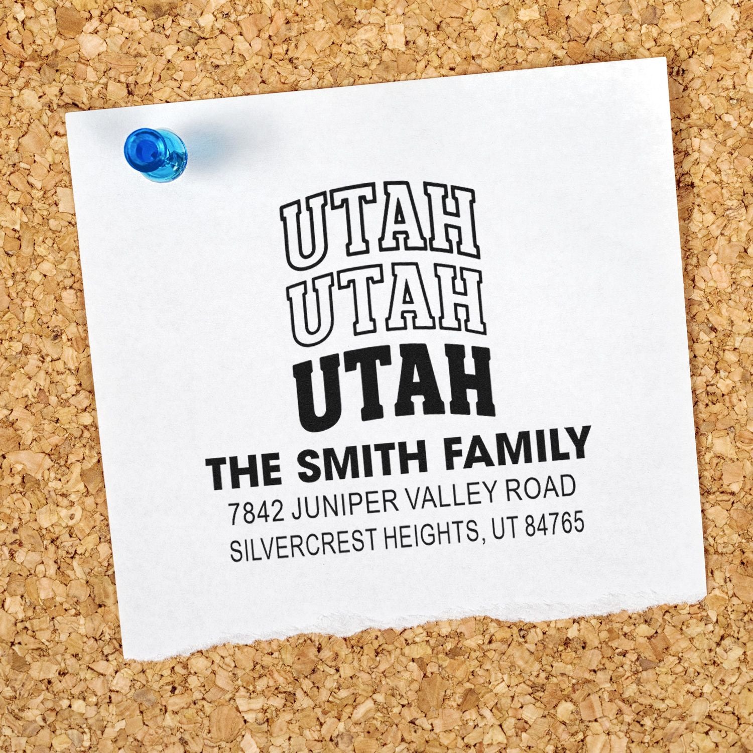 Custom Utah return address rubber stamp with family name and mailing address on paper pinned to a corkboard.