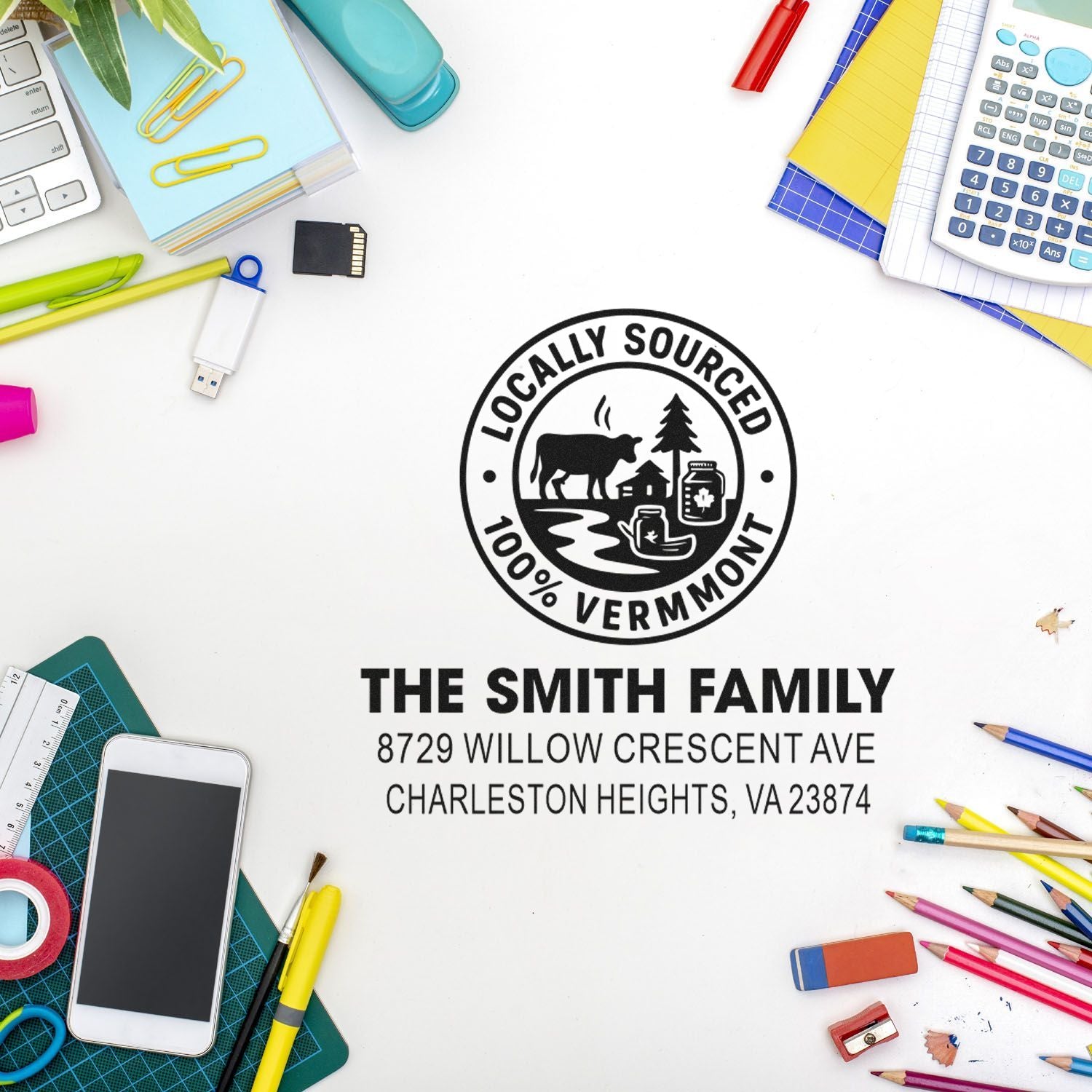 Personalized address stamp with Locally Sourced 100% Vermont logo and The Smith Family address, on a desk with pens, calculator, phone, and stationery.