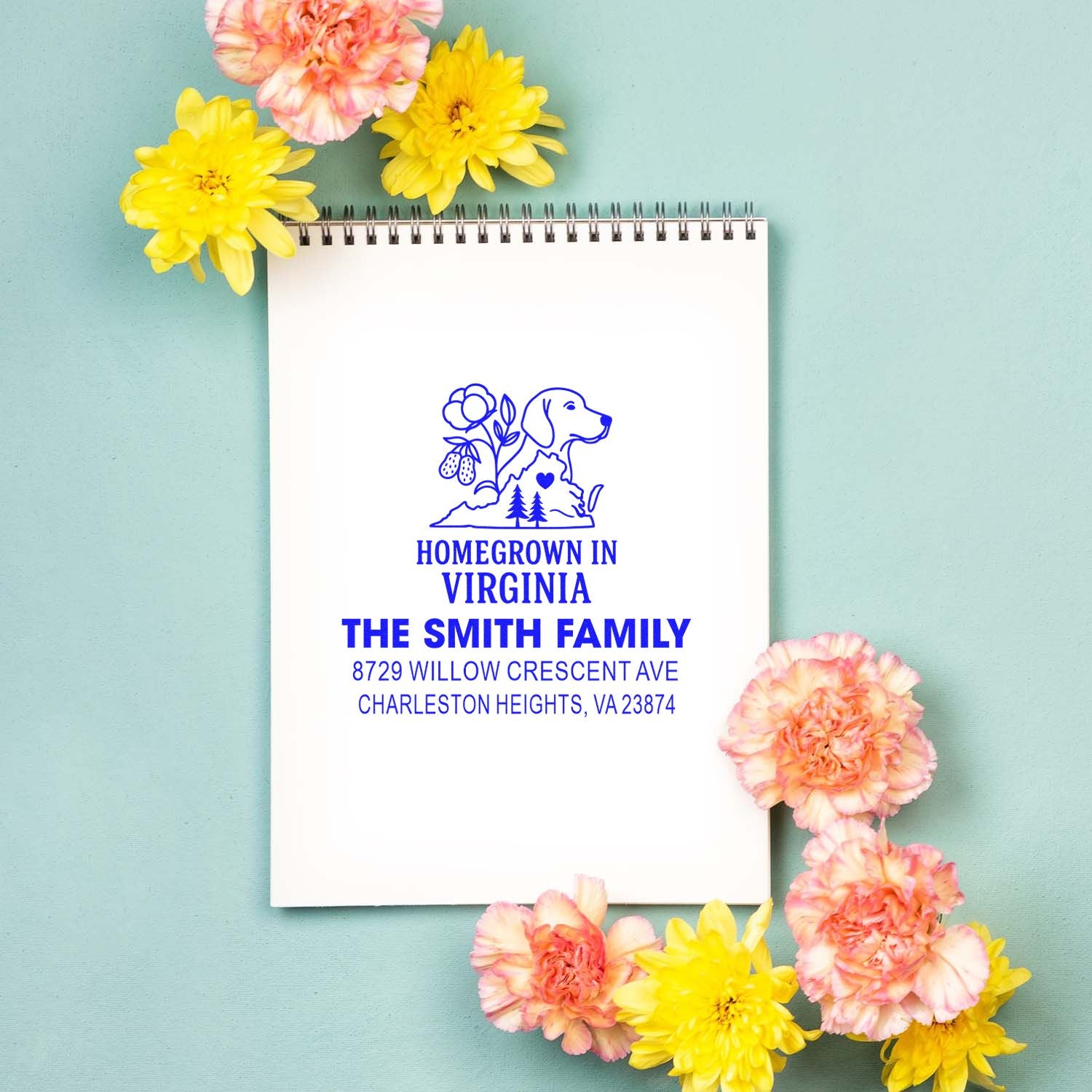 Custom blue Homegrown in Virginia family address stamp on a spiral notebook, styled with yellow and peach flowers on a mint background.
