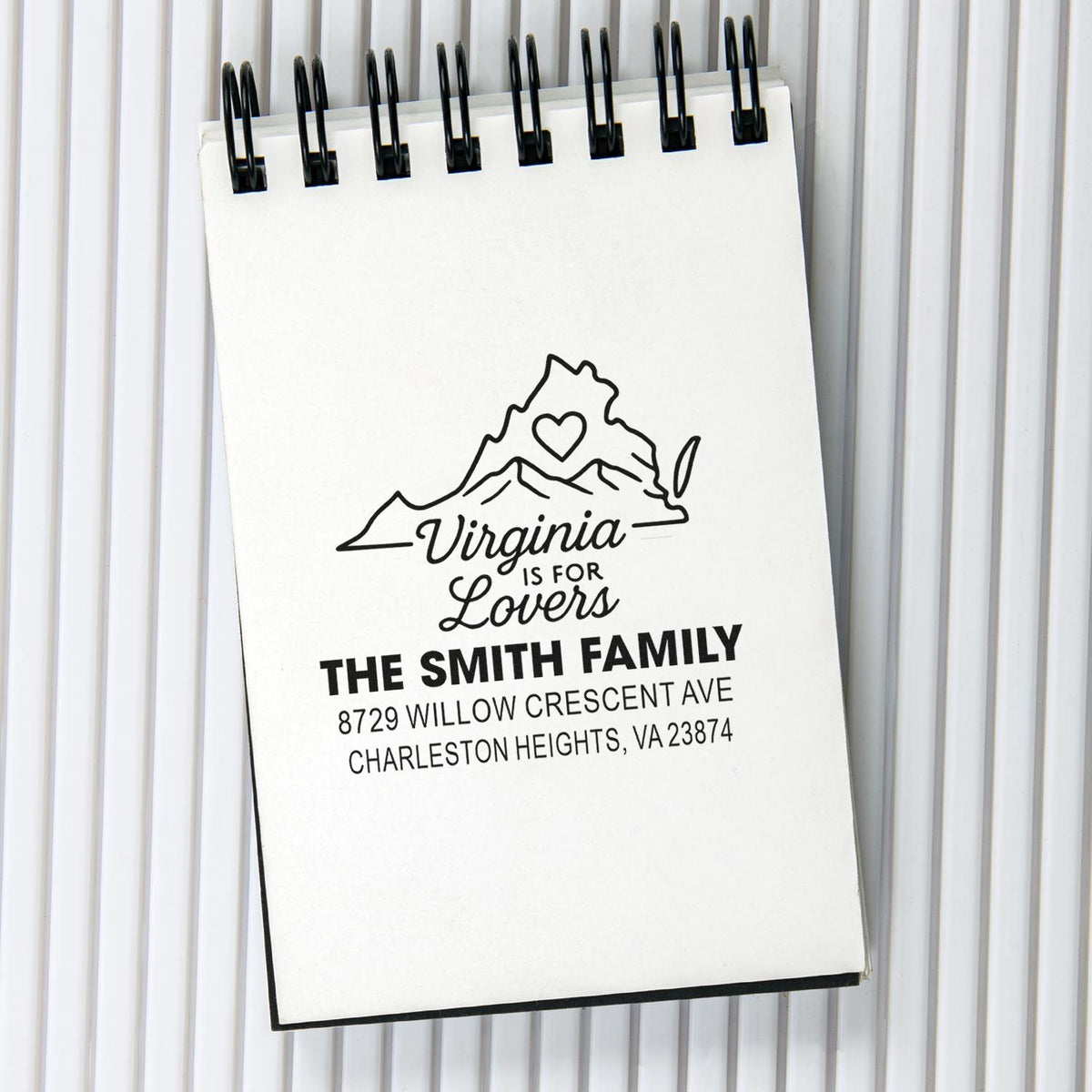 Custom Virginia address stamp on a white spiral notebook, featuring The Smith Family, mountain heart design, and Charleston Heights address.