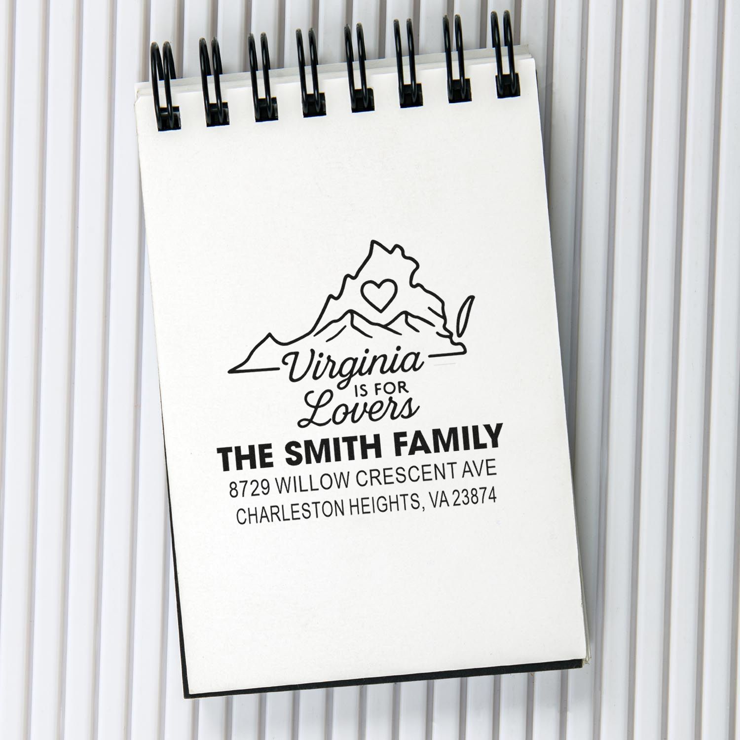 Personalized Virginia return address stamp on spiral notepad, featuring a mountain heart logo, The Smith Family name, and Charleston Heights address.