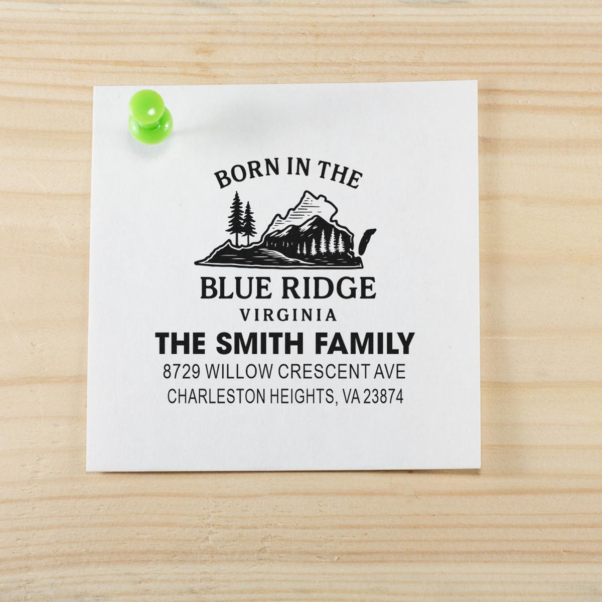 Personalized Blue Ridge, Virginia return address stamp for The Smith Family, pinned to white paper on a wooden desk with a green pushpin.