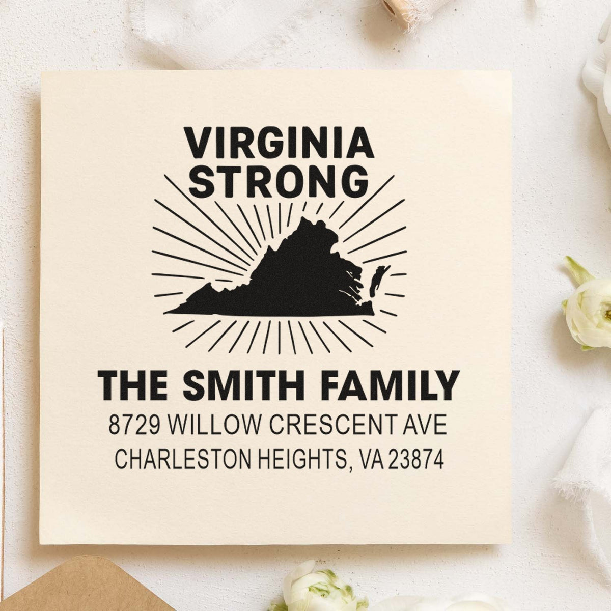 Custom Virginia Strong family address stamp on cream paper, featuring Virginia silhouette with sunburst rays and Smith family address, styled on a floral backdrop.