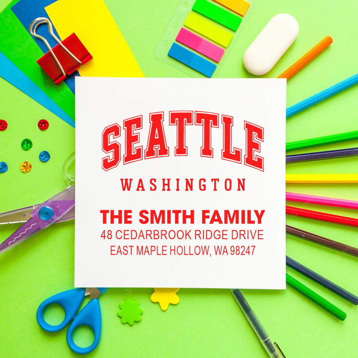 Custom Seattle Washington address stamp for The Smith Family on bright stationery with paper clips, scissors, pencils, and sticky notes.
