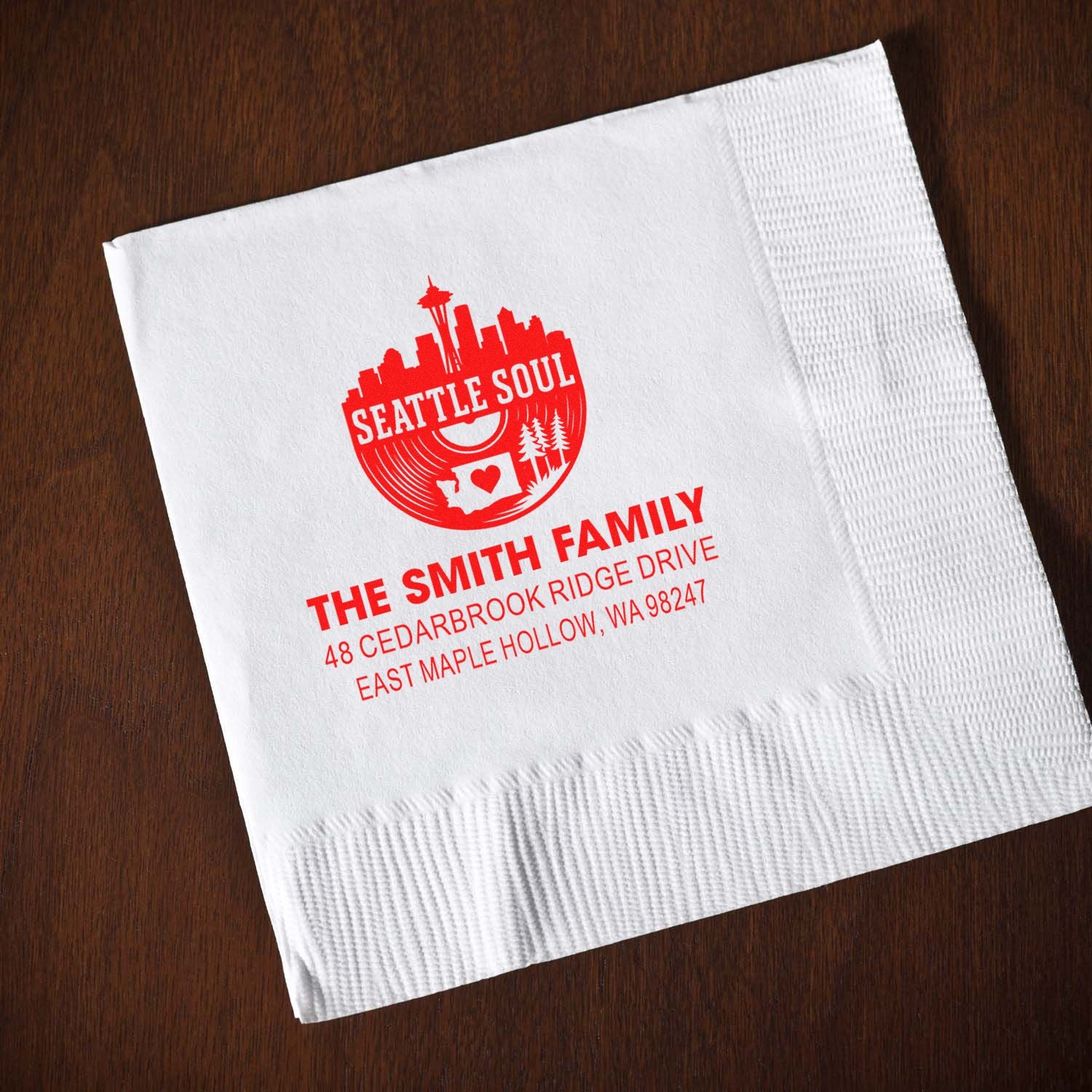 Custom Seattle Soul family address stamp on white cocktail napkin on a wooden table