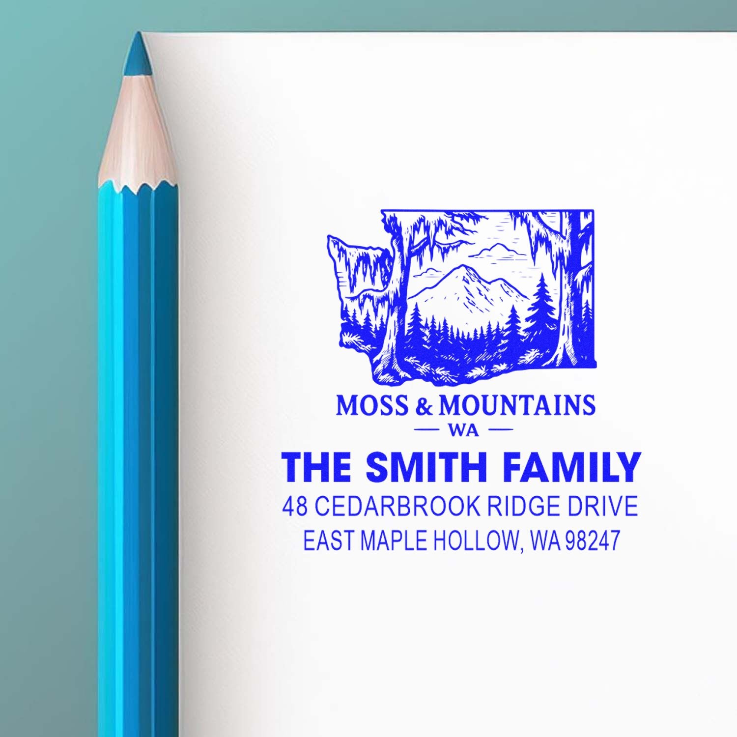 Custom blue address stamp for The Smith Family, featuring a Washington mountain forest graphic on white paper beside a blue pencil.