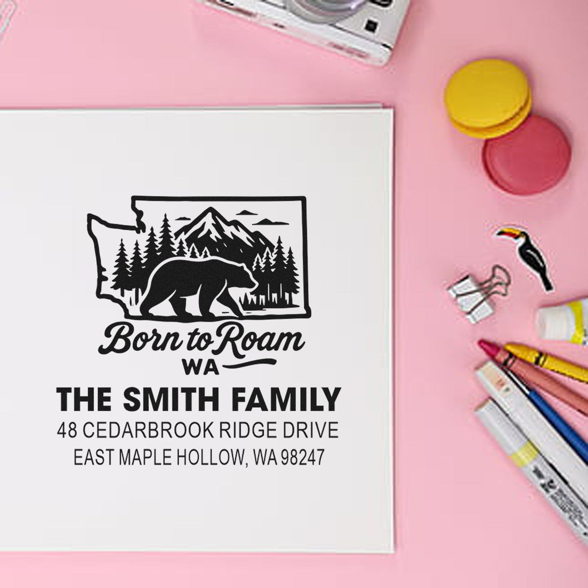Personalized Washington address stamp with bear and mountain design on white paper, shown on a pink desk with markers and ink pads.