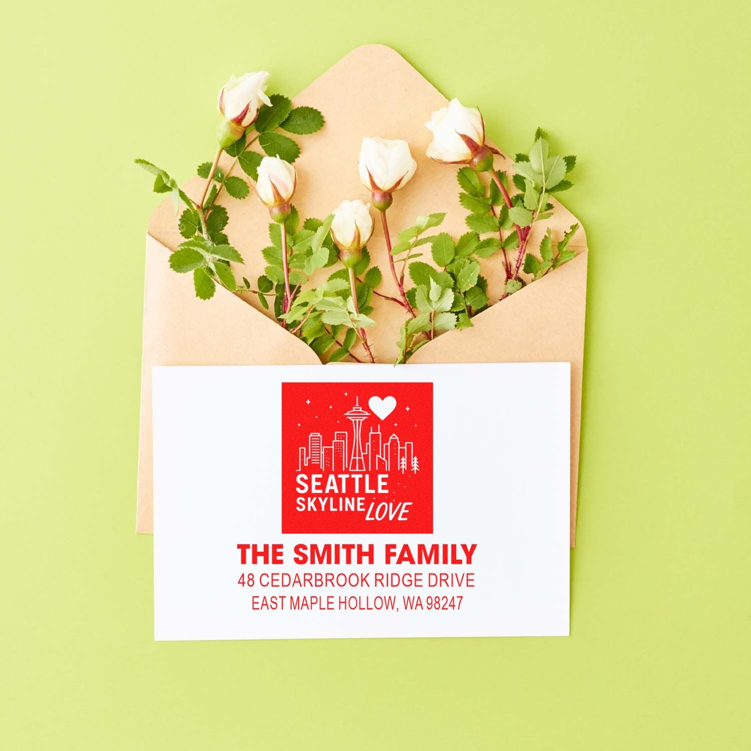 Custom Seattle Skyline Love address stamp on envelope with white roses, featuring The Smith Family return address on a green background.
