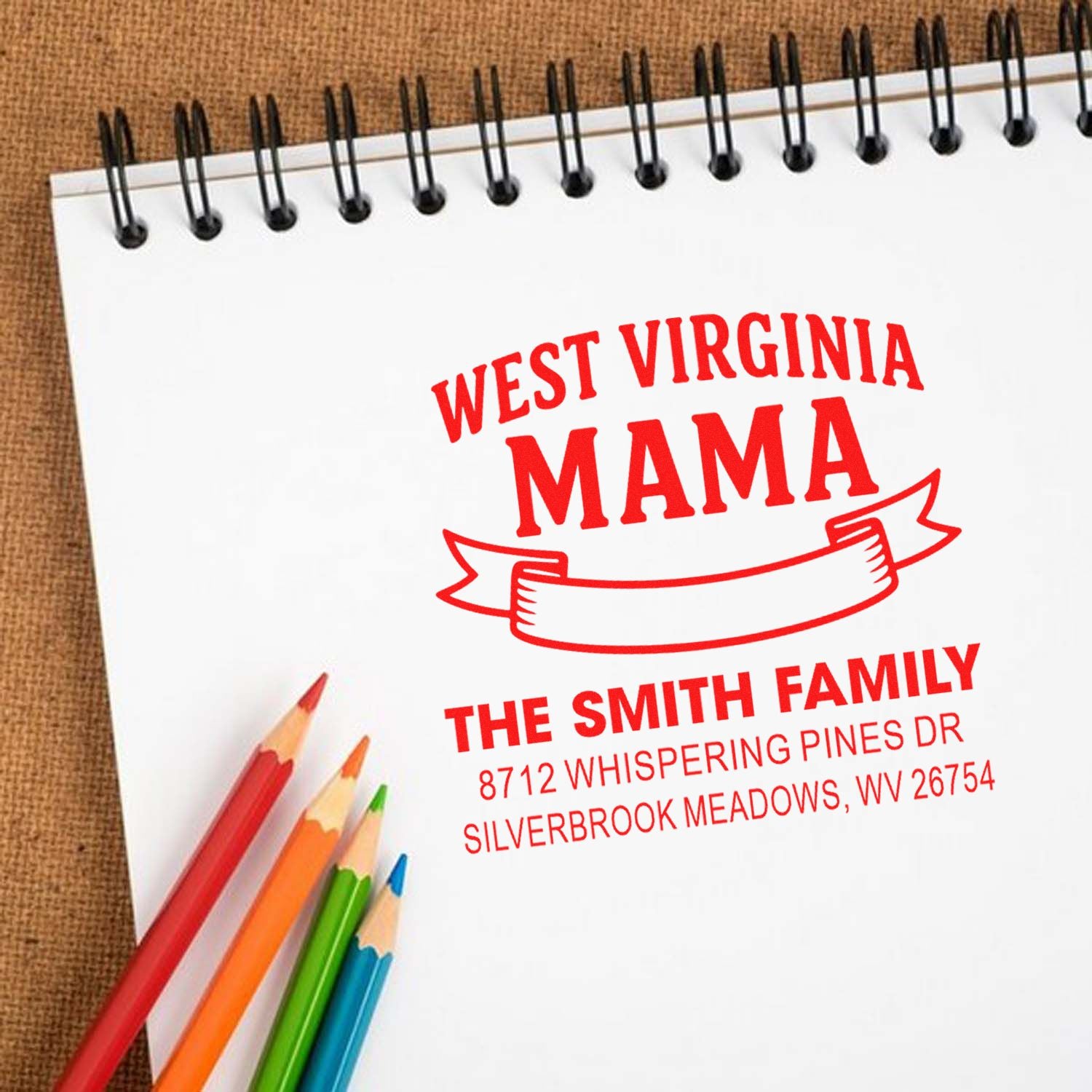 West Virginia Mama custom address stamp on a spiral notebook with colored pencils, featuring The Smith Family and Silverbrook Meadows, WV.