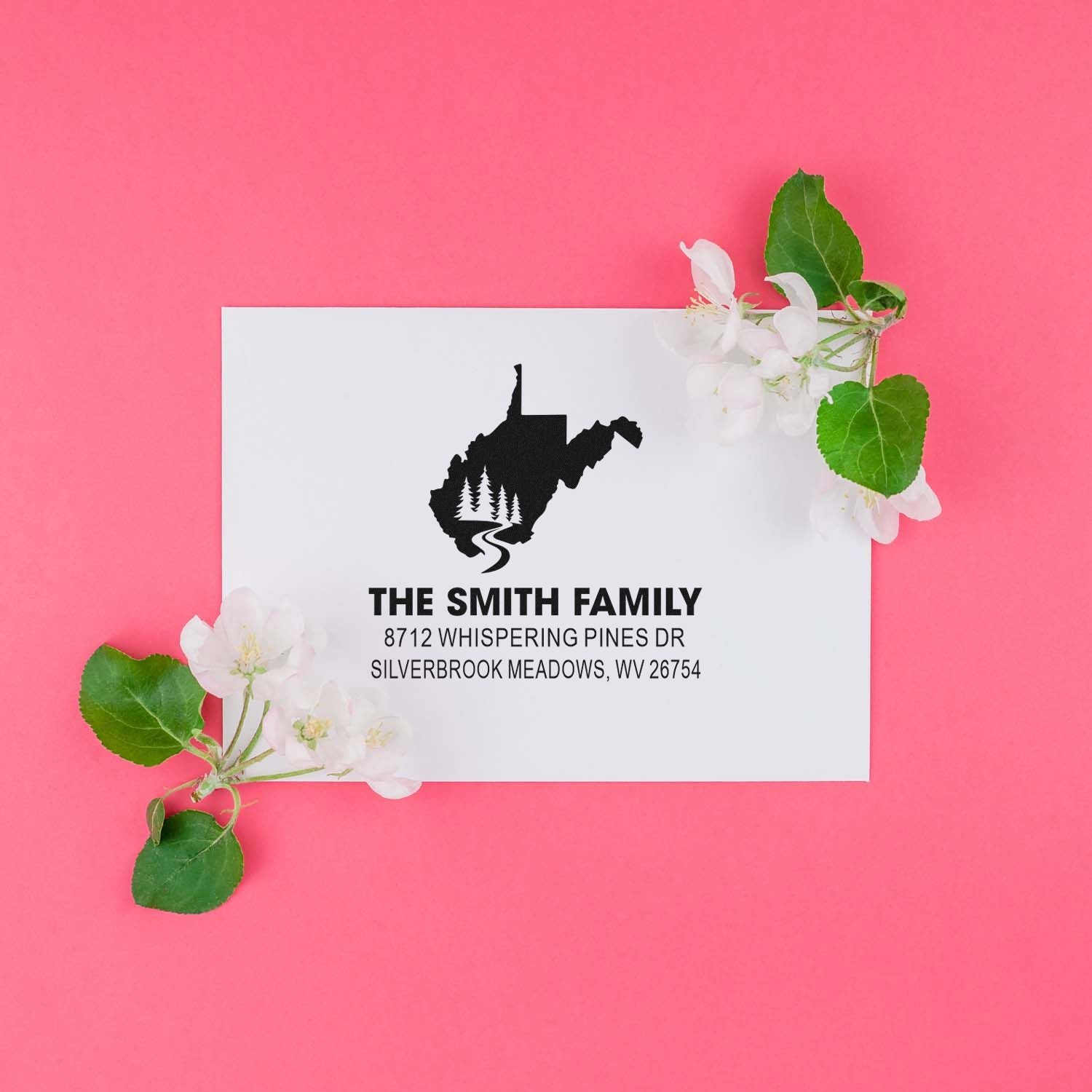 Custom address stamp for The Smith Family with West Virginia silhouette, set on a pink background and styled with white blossoms and green leaves.