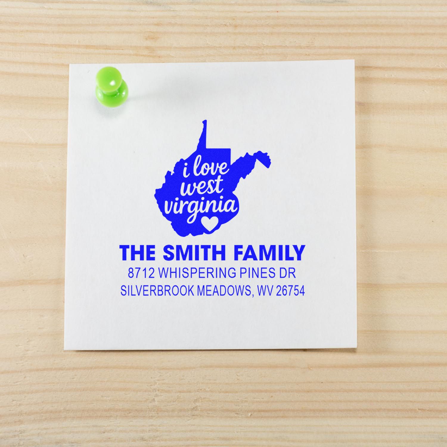 Custom West Virginia return address stamp on a white card pinned to a wood tabletop, featuring I love West Virginia and The Smith Family address.