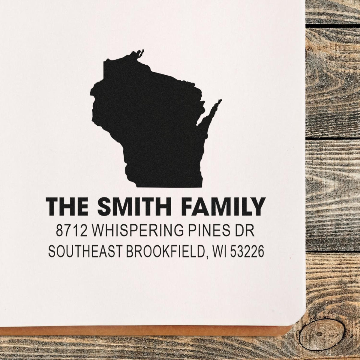 Custom address stamp for The Smith Family with Wisconsin silhouette, shown on white paper over a rustic wood table.