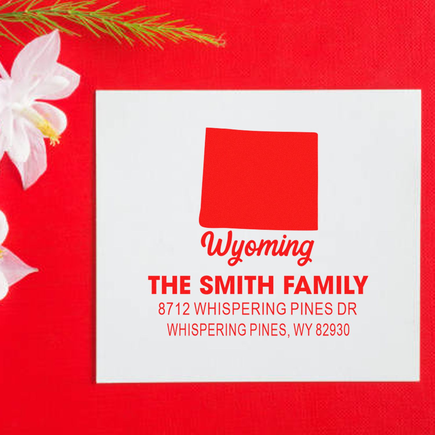 Custom Wyoming address stamp for The Smith Family, shown on a red holiday-themed background with white card and floral accent.