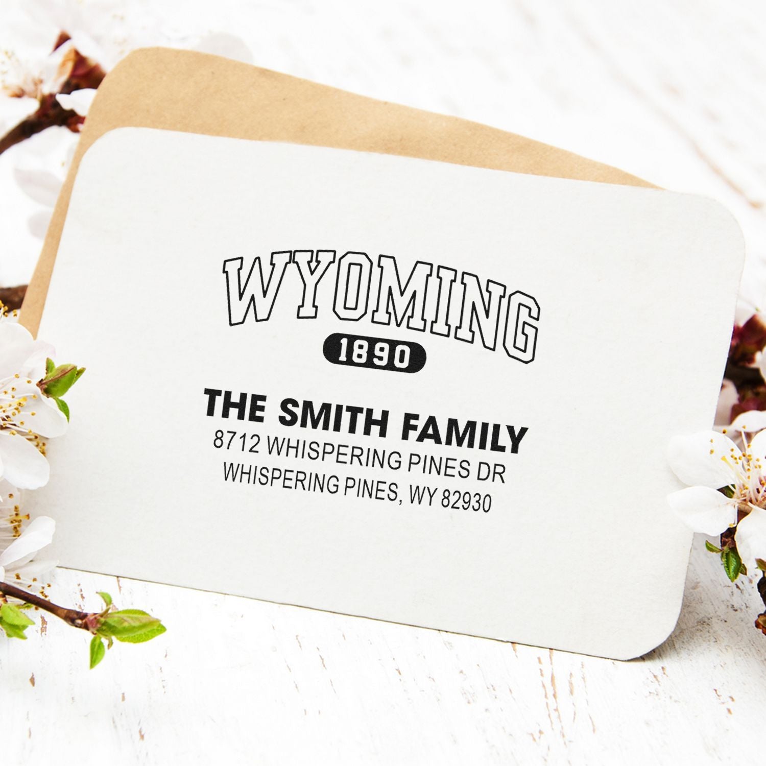 Custom Wyoming 1890 address stamp for The Smith Family on a white card over a kraft envelope, styled with spring blossoms