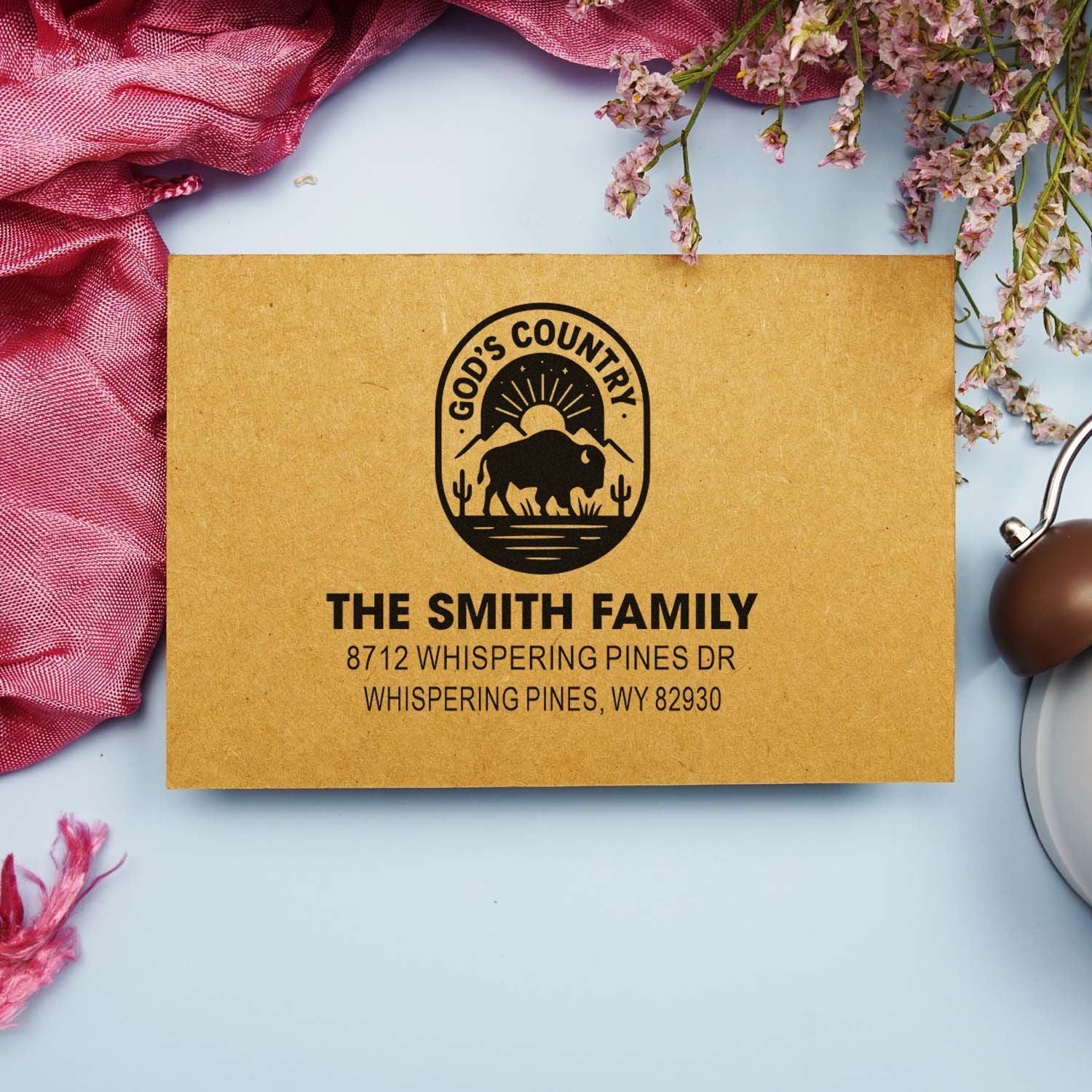 Custom address stamp on kraft envelope mockup with Gods Country bison logo, The Smith Family name, and Whispering Pines address.