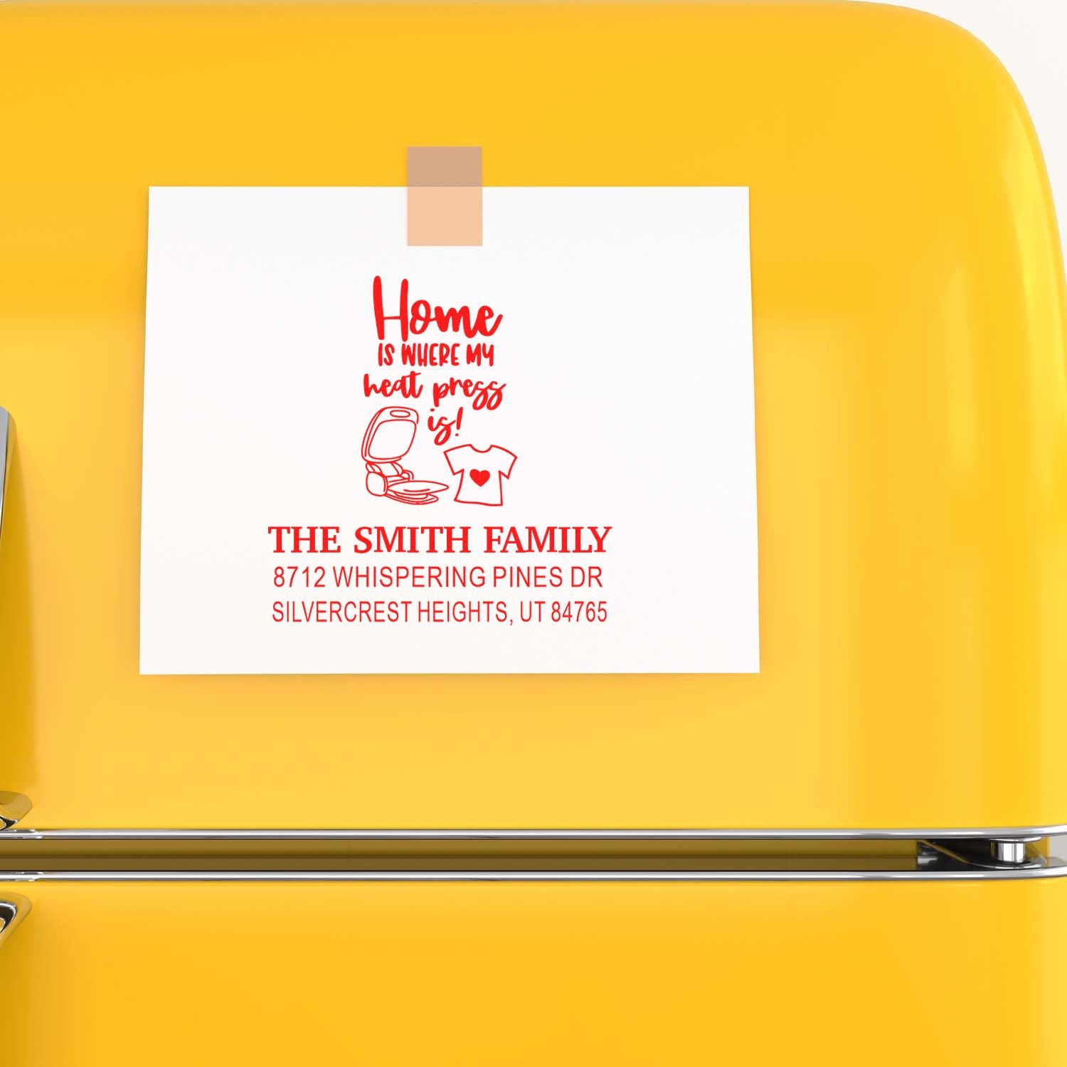 Custom return address stamp on white card taped to a bright yellow fridge, featuring Home is where my heart press is! with family name and address.