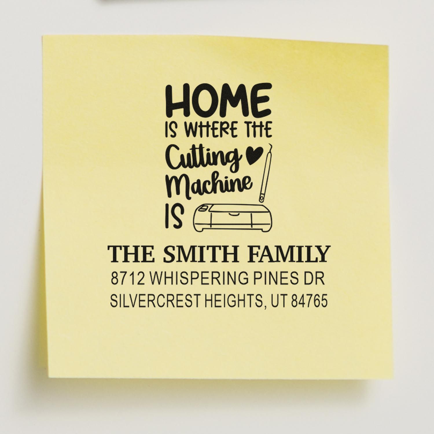 Personalized address stamp on yellow paper reading Home is where the cutting machine is for The Smith Family, with machine icon.