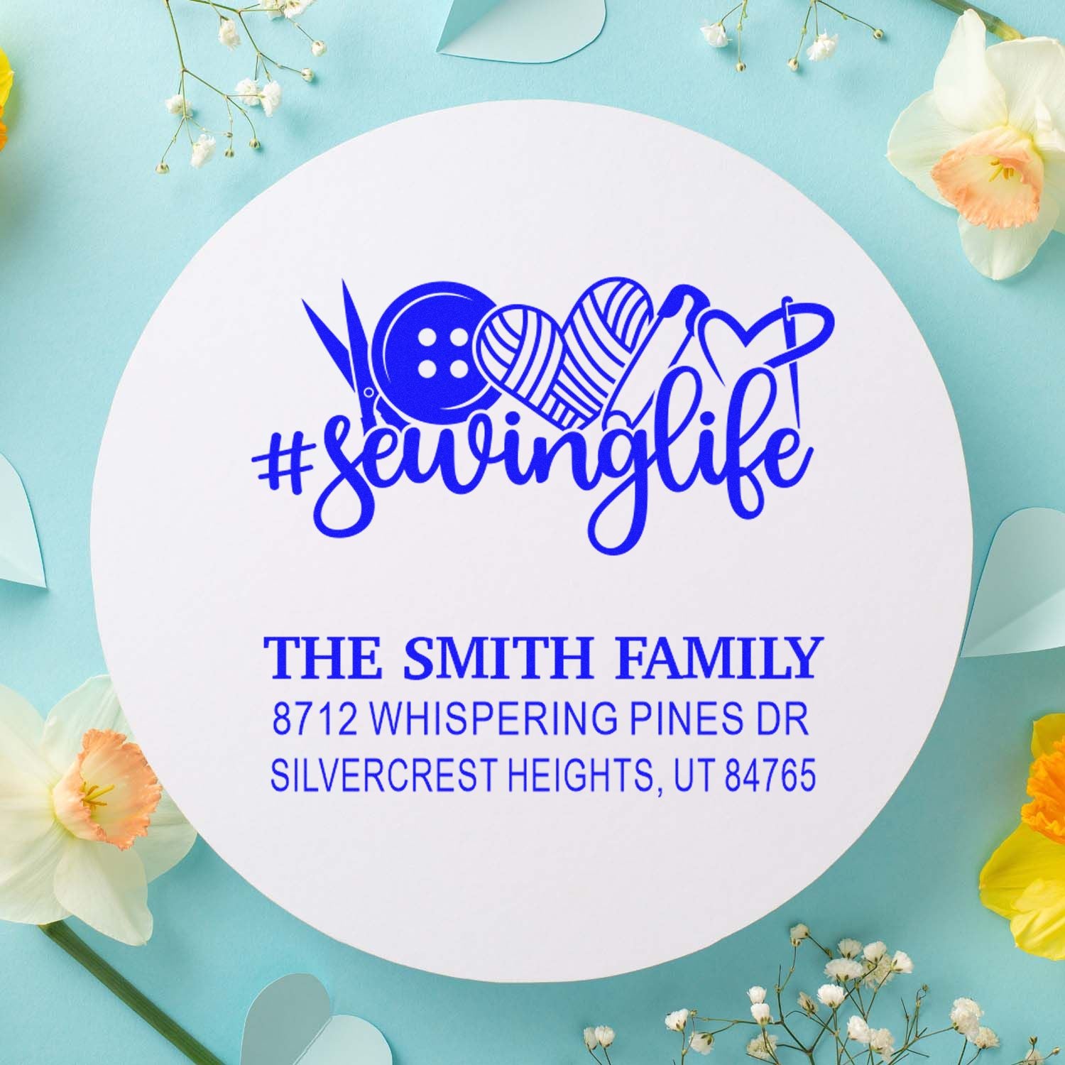 Custom sewing-themed address stamp with #sewinglife, thread, button and heart icons on a pastel floral background for The Smith Family.