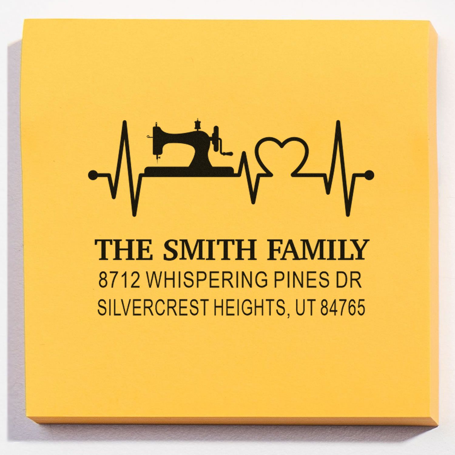 Yellow personalized family address stamp with sewing machine and heartbeat heart design, reading The Smith Family and Silvercrest Heights, UT 84765.